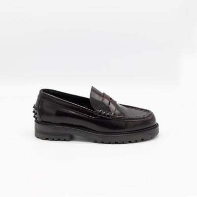 Chunky loafer in burgundy patent leather with rigid rubber soles and rubber pebbles on heel. 