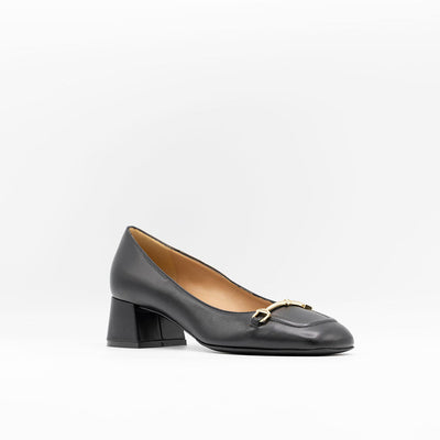 Heeled pump made from smooth black calf leather, featuring a square-shaped toe with a gold metallic horse-bit buckle