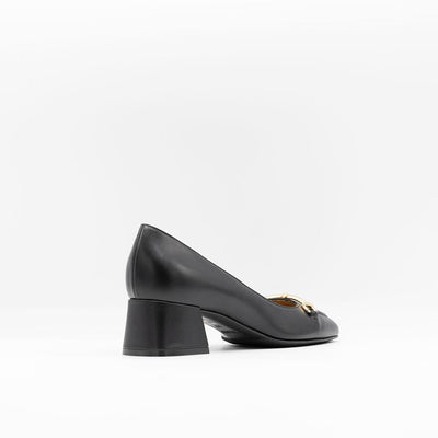 Heeled pump made from smooth black calf leather, featuring a square-shaped toe with a gold metallic horse-bit buckle